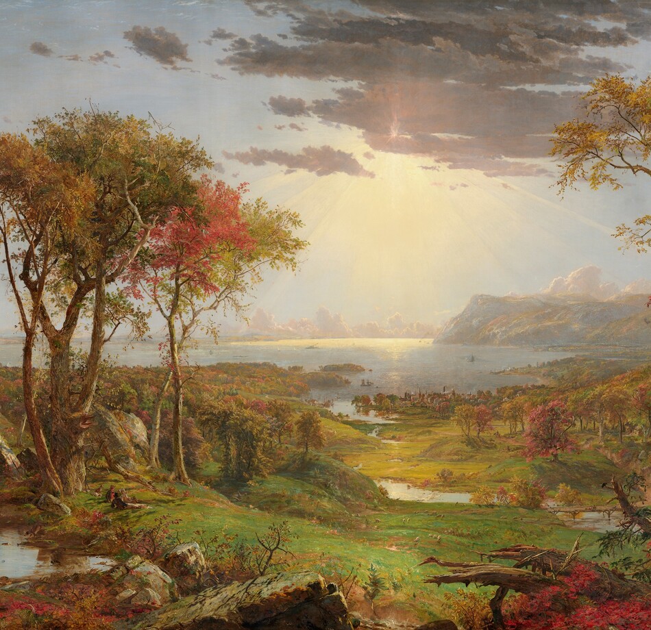 We look out onto a sweeping, panoramic view with trees, their leaves fiery orange and red, framing a view of a distant body of water under a sun-streaked sky in this long, horizontal landscape painting. The horizon comes about halfway up the composition, and is lined with hazy mountains and clouds in the deep distance. Close examination slowly reveals minuscule birds tucked into the crimson-red, golden yellow, and deep, sage-green leaves of the trees to either side of the painting. Closest to us, vine-covered, fallen tree trunks and mossy gray boulders line the bottom edge of the canvas. Beyond a trickling waterfall and small pool near the lower left corner, and tiny within the scale of the landscape, a group of three men and their dogs sit and recline around a blanket and a picnic basket, their rifles leaning against a tree nearby. The land sweeps down to a grassy meadow crossed by a meandering stream that winds into the distance, at the center of the painting. Touches of white and gray represent a flock of grazing sheep in the meadow. A low wooden bridge spans the stream to our right, and a few cows drink from the riverbank. Smoke rises from chimneys in a town lining the riverbank and shoreline beyond, and tiny white sails and steamboats dot the waterway. Light pours onto the scene with rays like a starburst from behind a lavender-gray cloud covering the sun, low in the sky. The artist signed the painting as if he had inscribed the flat top of a rock at the lower center of the landscape with his name, the title of the painting, and date: “Autumn – on the Hudson River, J.F Cropsey, London 1860.”