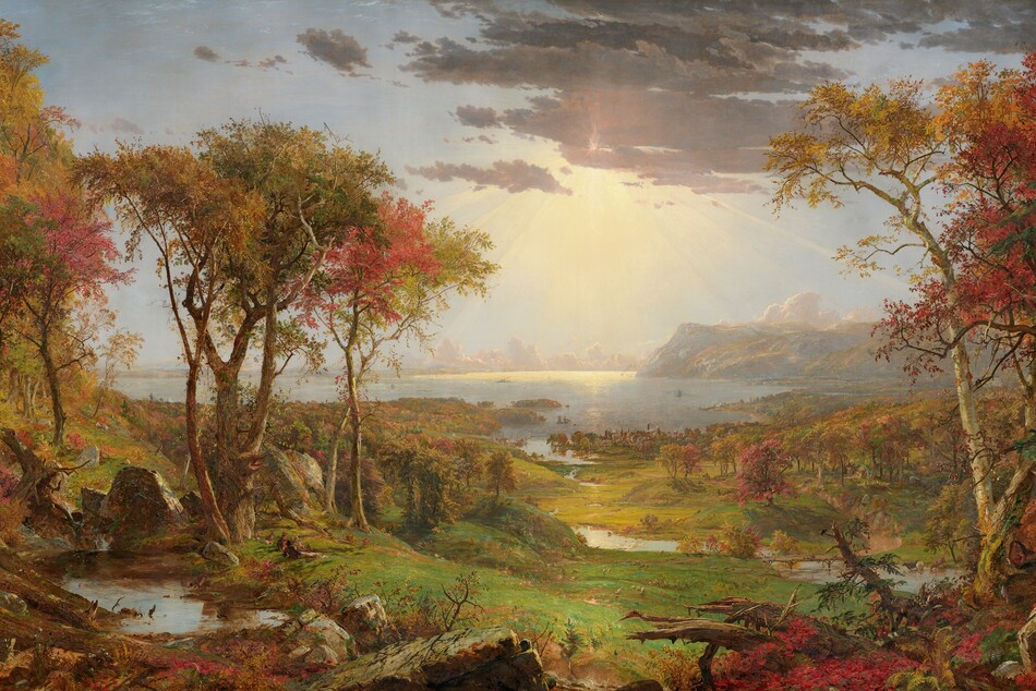 We look out onto a sweeping, panoramic view with trees, their leaves fiery orange and red, framing a view of a distant body of water under a sun-streaked sky in this long, horizontal landscape painting. The horizon comes about halfway up the composition, and is lined with hazy mountains and clouds in the deep distance. Close examination slowly reveals minuscule birds tucked into the crimson-red, golden yellow, and deep, sage-green leaves of the trees to either side of the painting. Closest to us, vine-covered, fallen tree trunks and mossy gray boulders line the bottom edge of the canvas. Beyond a trickling waterfall and small pool near the lower left corner, and tiny within the scale of the landscape, a group of three men and their dogs sit and recline around a blanket and a picnic basket, their rifles leaning against a tree nearby. The land sweeps down to a grassy meadow crossed by a meandering stream that winds into the distance, at the center of the painting. Touches of white and gray represent a flock of grazing sheep in the meadow. A low wooden bridge spans the stream to our right, and a few cows drink from the riverbank. Smoke rises from chimneys in a town lining the riverbank and shoreline beyond, and tiny white sails and steamboats dot the waterway. Light pours onto the scene with rays like a starburst from behind a lavender-gray cloud covering the sun, low in the sky. The artist signed the painting as if he had inscribed the flat top of a rock at the lower center of the landscape with his name, the title of the painting, and date: “Autumn – on the Hudson River, J.F Cropsey, London 1860.”