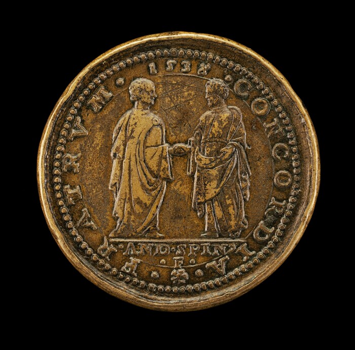 This is a photograph of an ancient coin. The coin features a detailed engraving of two robed figures in profile, facing each other and reaching out their hands. Surrounding the figures is an inscription that includes the year "1532" and the text "CONCORDIA." The edges of the coin are slightly worn, and there is a raised, beaded border encircling the figures and inscriptions. The overall patina is a muted, aged bronze.
