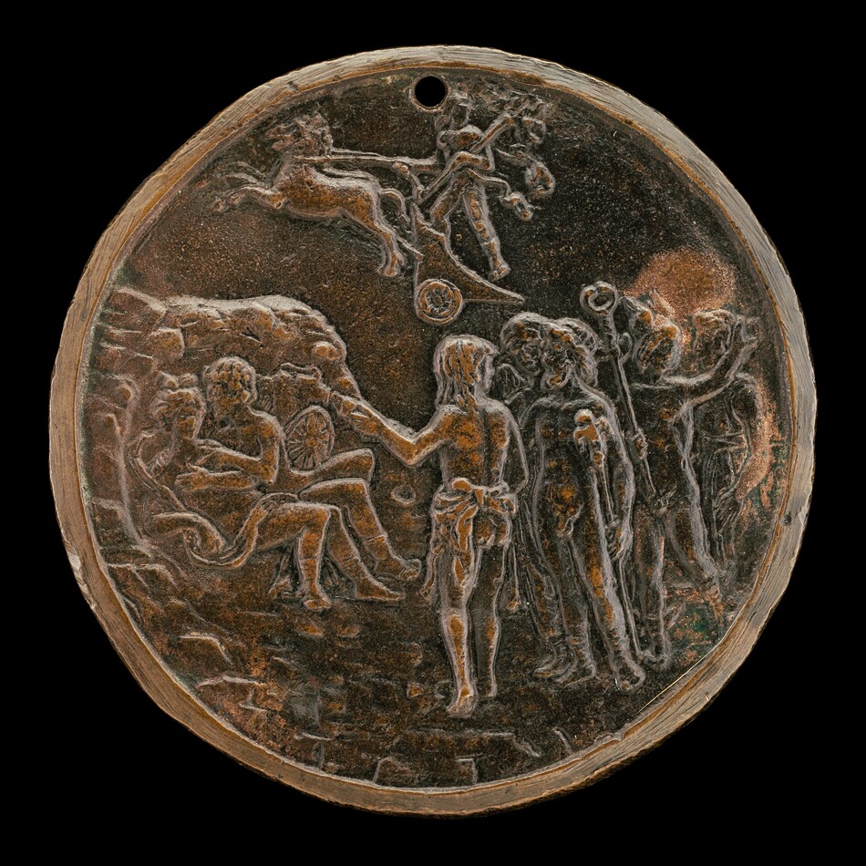 The sculpture is a circular relief medallion depicting a scene with multiple human figures and a chariot at the top. The figures are engaged in various activities, with some sitting and others standing. The sculpture is brown and likely made of bronze or a similar metal, giving it an aged patina. The figures are intricately carved, providing depth and movement, with attention to detail. The chariot at the top adds to the action-oriented narrative. The medallion has a small hole at the upper edge.