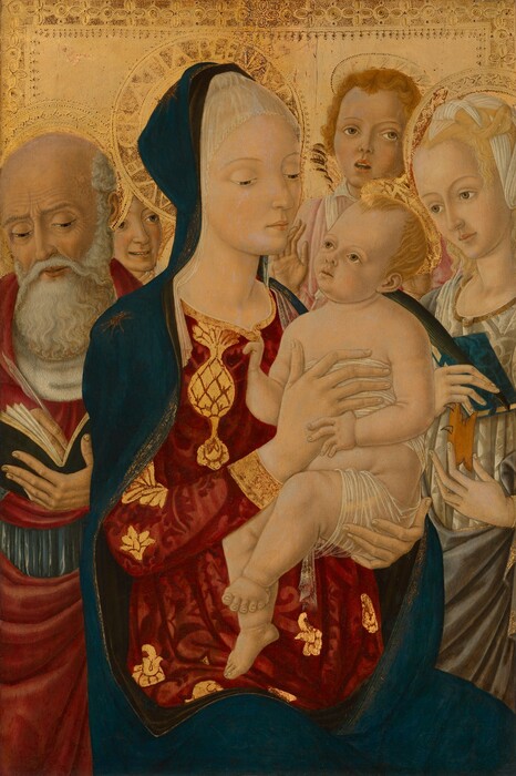 Shown from the thighs up, a woman holding a baby is surrounded by a man, woman, and two winged angels in this vertical painting. Mary, the central woman, the baby, Jesus, and the other woman, Saint Catherine of Alexandria, have pale, peach-toned skin. The man, Saint Jerome, and two angels have slightly darker peach-colored skin with faint gray shading. They all have gold halos, wide-set, hooded, light brown eyes, long, straight noses, delicate mouths, and pointed chins where we can see. Mary sits with her knees angled to our right, and she looks down at the baby held sitting upright near that shoulder. The crown of her head is covered by a white veil down to her forehead. A lapis-blue cloak drapes over the back of her head, her shoulders, and across her lap. There is a gold starburst on the right shoulder, to our left, and the cloak is edged in gold. The dress she wears is patterned ruby red on garnet red and decorated with shimmering, bright gold designs. She supports Jesus’s bottom with her left hand, to our right, and braces his chest with her other hand. He has small features with chubby cheeks, a high hairline with blond hair, and a chubby body. He grips the neckline of her dress with his right hand, to our left, and touches the hand that holds his chest with the other. He is nude except for a translucent white cloth around his chest and hips. To our left, Saint Jerome looks down at and writes in a book with a dark green cover using a feather quill. He is balding and has a long white beard. His forehead is lined, his cheeks hollow, and his lips parted. He wears a red robe over a white garment with a white collar. To our right, Saint Catherine looks at Jesus and holds a blue-covered book and black quill pen in one hand and a fragment of a wooden wheel lined with spikes with the other. Her blond hair is wrapped with and around a white cloth, and she wears a white-on-white patterned dress under a silver-gray cloak. One angel looks on from between Mary and the other looks up and to our right from behind Jesus. Both have their lips parted. The one to our right wears a pale pink garment and holds up one hand. The background is shiny, bright gold punched along the top and upper corners with a geometric design.