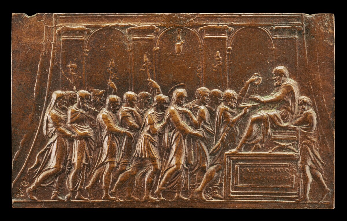 The sculpture depicts a bas-relief scene with multiple figures forming a procession or gathering. On the left, a line of individuals face towards a seated figure on the right. The prominent figure is elevated with one hand extended. The figures are draped in classical robes, giving it an ancient or historical setting. The sculpture is made of bronze, with a dark brown appearance and highlights where light catches on raised surfaces. The background features arches or columns, adding to the classical architectural context. The scene appears to be a formal or ceremonial gathering with a focus on the seated figure.