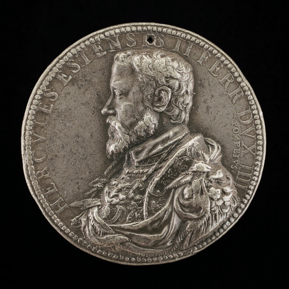 The sculpture depicts a relief portrait of a man in profile facing left. The man is adorned in intricate clothing and has short, curly hair and a full beard. There is an inscription in raised letters around the edge. The material appears metallic and the sculpture has a small hole for hanging. The fine detail emphasizes the man's facial features and attire.
