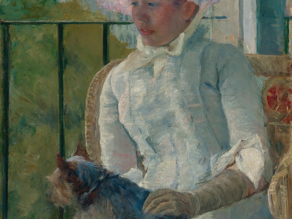 Shown from the knees up, a young woman wearing a white gown and bonnet sits in front of a balcony railing on a sunny day, holding a small dog on her lap in this vertical portrait painting. The scene is painted with visible brushstrokes, which are especially broad in the background and clothing. The woman sits with her body angled to our left, and she looks down in that direction with blue eyes. She has a short, snub nose, rosy cheeks, and her full, pink lips are parted. The woman’s bonnet is tied under her chin with a pale yellow bow. Her dress has a tightly-fitting bodice, elbow-length sleeves, and a long skirt. The bonnet and dress are painted with strokes of faint sky blue, petal pink, lavender purple, and mint green, with cream-white highlights and some darker cobalt-blue and apricot-peach strokes for shading. The dog on her lap lies with its head to our left, lifted as it looks out onto the landscape. The tan glove the woman wears on the arm we can see reaches her elbow, and she rests that hand on the dog’s back. Her right arm, to our left, is hidden below the elbow by the dog. The animal has charcoal-gray fur along its back and tan fur on the legs and shaggy face. The woman sits in a wicker armchair with a crimson-red medallion next to her left shoulder, to our right. The black balcony railing spans the width of the painting at the level of her nose, and has vertical bars. In the landscape beyond, trees to the right are painted loosely with sage green and mustard yellow. Buildings in the distance fill the top quarter of the composition, and are loosely painted with strokes of slate and aquamarine blue. The sky above is streaked with pale blush pink and ice blue. The artist signed the painting in the lower right corner, “Mary Cassatt.”