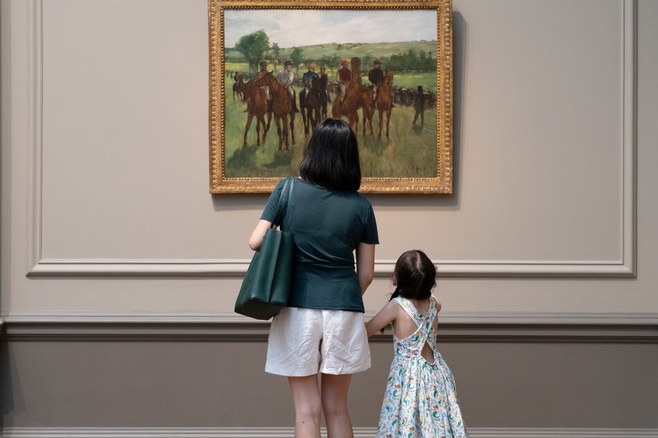 A parent and child look at Edgar Degas's The Riders together