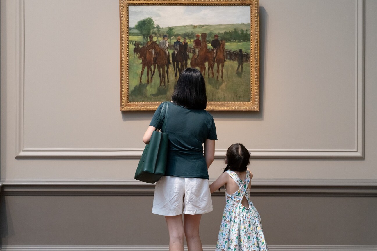 A parent and child look at Edgar Degas's The Riders together