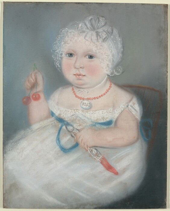 The image shows a young child seated and facing forward. The child has soft facial features, fair skin, rosy cheeks, light blue eyes, and is wearing a white dress with blue ribbon accents. They wear a white bonnet with lace. The child is holding cherries and a rattle-like toy. They wear a coral bead necklace with a pendant displaying the number "118." The background is a muted blue-gray color.