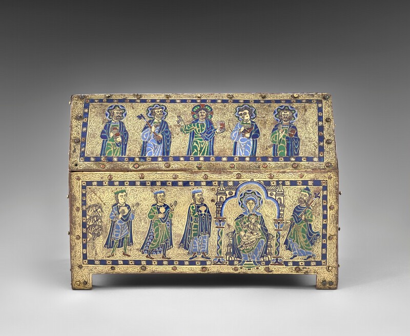 A free-standing, gold, enameled, rectangular box has a triangular top like the roof of a house, and the box rests on a short, square foot in each corner. In this photograph, we look onto one long side and the short side to our right is angled toward us, so we see the panel there, too. Along the long side, five people are shown from the waist up in the upper, roof-like panel and six more line up on the panel below. The skin of every person is gold, and all wear robes and garments in lapis or sky blue, spring green, yellow, and white. The area around the people is also gold, and each panel is encased by a royal-blue band dotted with stylized stars at regular intervals. Each panel is then lined with small, button-like rounded bosses around its edges. In the upper panel, all of the men except the second from the right have beards, and all have halos with wavy bands of blue, green, yellow, and white. The man to our left holds a book and his neighbor a skeleton key the length of his arm. The man at the center holds up a book with his left hand, on our right, and raises the index and middle fingers of his other hand, held up at shoulder height. The two men to our right also hold books. In the panel below, three horses’ heads peek in from the left edge, creating a vertical band, and three crowned men line up, holding gold vessels and looking toward a woman seated in a throne with a child on her lap. The woman has a halo made with a wavy pattern of blue, yellow, green, black, and white. Her throne is flanked by columns, and the area around it is edged with bands of white, light, and dark blue. The baby wears gold, has a halo, holds a book in his lap with his left hand, and raises the first two fingers of his other hand toward the three men. The final person in this panel wears a hat, holds a scepter topped with a fleur-de-lis, and gestures at the woman and baby. The head and shoulders of a haloed person is visible along the short side of the box, which is angled sharply away from us. The gold between all the people and bordering each panel is intricately carved with tiny flowing organic lines and swirls.