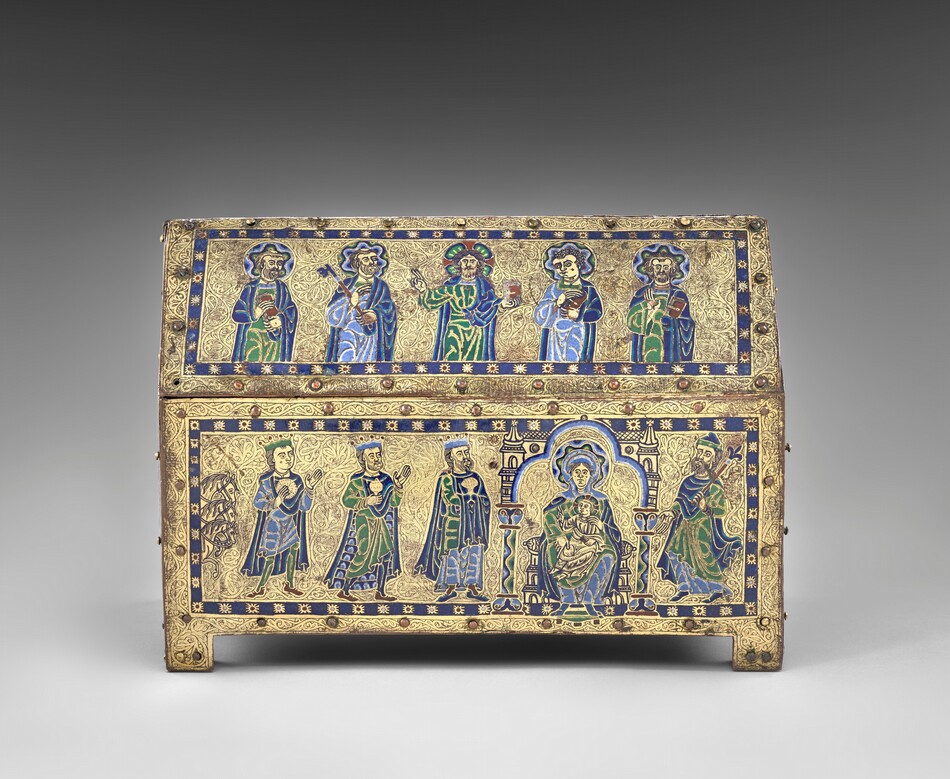 A free-standing, gold, enameled, rectangular box has a triangular top like the roof of a house, and the box rests on a short, square foot in each corner. In this photograph, we look onto one long side and the short side to our right is angled toward us, so we see the panel there, too. Along the long side, five people are shown from the waist up in the upper, roof-like panel and six more line up on the panel below. The skin of every person is gold, and all wear robes and garments in lapis or sky blue, spring green, yellow, and white. The area around the people is also gold, and each panel is encased by a royal-blue band dotted with stylized stars at regular intervals. Each panel is then lined with small, button-like rounded bosses around its edges. In the upper panel, all of the men except the second from the right have beards, and all have halos with wavy bands of blue, green, yellow, and white. The man to our left holds a book and his neighbor a skeleton key the length of his arm. The man at the center holds up a book with his left hand, on our right, and raises the index and middle fingers of his other hand, held up at shoulder height. The two men to our right also hold books. In the panel below, three horses’ heads peek in from the left edge, creating a vertical band, and three crowned men line up, holding gold vessels and looking toward a woman seated in a throne with a child on her lap. The woman has a halo made with a wavy pattern of blue, yellow, green, black, and white. Her throne is flanked by columns, and the area around it is edged with bands of white, light, and dark blue. The baby wears gold, has a halo, holds a book in his lap with his left hand, and raises the first two fingers of his other hand toward the three men. The final person in this panel wears a hat, holds a scepter topped with a fleur-de-lis, and gestures at the woman and baby. The head and shoulders of a haloed person is visible along the short side of the box, which is angled sharply away from us. The gold between all the people and bordering each panel is intricately carved with tiny flowing organic lines and swirls.