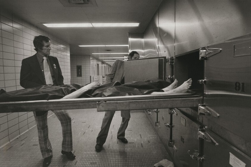 Homicide detectives produce fingerprints from a corpse in the city morgue, New York City