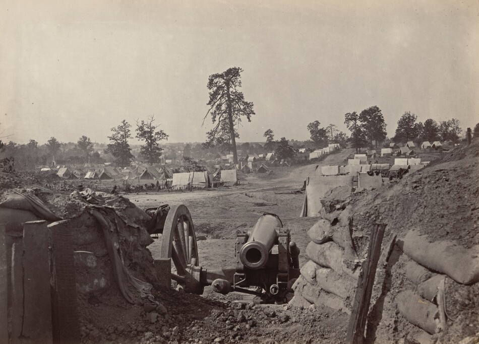 The image shows an artillery position with a cannon behind a barricade of earth and sandbags. In the background, there is a line of trees with a lone taller tree slightly right of center. Beyond the cannon, there is an encampment with rows of tents arranged neatly. The landscape has a historical photograph style with monochromatic tones, giving a dusty atmosphere. The color palette is sepia-like browns and grays.