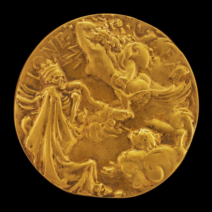 The image shows a circular gold medallion or coin with a sculpted design. The design features multiple figures: a skeletal figure on the left wearing a crown and holding a garment, and more dynamic figures on the right with human and possibly mythical elements like wings or flowing hair, arranged in a swirling composition. The sculpture is crafted from gold, with intricate details in the relief work giving it a radiant appearance against a black background.
