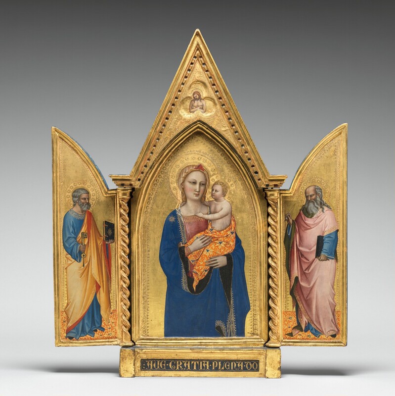 Two panels on a gilded, carved, wooden frame are swung open like shutters to show a bearded, gray-haired man wearing robes standing in each wing, on either side of panel with a pointed, arched top showing a woman holding a baby. In a three-lobed shape in the apex above the woman and child, a nude man crosses his arms over his chest. All the people have pale, ivory-colored skin. Gold halos encircle each person’s head and the background of all three panels is bright gold. The woman in the center panel is shown from the hips up with her body facing us. The deep blue mantle that drapes over her shoulders and her dusty rose-pink dress beneath are trimmed in gold. A sheer veil covers her wavy blond hair and a red, triangular form sits above her forehead like a diadem. She looks to our right with dark, almond-shaped eyes. She has a straight nose, her coral-pink lips are closed, and her smooth cheeks are lightly flushed with pale pink. She holds the child in the crook of her left arm, on our right, and rests her other hand in the baby’s lap. He has short, curly blond hair and looks directly at the woman. He reaches his right arm, farther from us, around his mother’s neck and hooks his other hand in the neckline of her dress. He wears a sheer shirt edged in gold, and the fabric draped around his hips is patterned with tangerine-orange and gold, with lapis-blue clover designs. He has rounded cheeks and a pudgy tummy, but his facial features and arms are scaled more like an adult. Twisted columns separate this central panel from the shutter-like panels to each side. A single person stands in each wing, filling most of the space, and both are angled and look towards the central panel. Both men have darker, olive-toned complexions, wear long robes trimmed in gold, and stand on floors patterned with orange, gold, and sparsely spaced royal blue diamond-shapes. The man to our left has short, steel-gray hair and a trimmed beard. Wrinkles line his forehead, and his brow is furrowed. He wears a topaz-blue, long sleeved garment under a honey-orange robe, the underside of which is ruby-red where it turns back over his wrists and shoulder. He holds a book with a dark cover up in his left hand, farther from us, and a large skeleton key in his other hand. In the right panel, a balding man has a fringe of long, gray hair and a flowing, full beard. His forehead is also creased with wrinkles and his brow is furrowed. The dark, olive-green lining of his rose-pink robe shows where it folds back at his neck, over his wrists, and down the front. His robe covers a topaz-blue garment as well. He holds a book, also with a dark cover, by his side with his left hand, closer to us, and holds up a feather quill with his opposite hand. The inner edges of each of the central panel and both wings are incised with bands of decorative floral and geometric designs punched into the gold backgrounds. In the pointed peak above the central panel, the nude man is shown from the waist up in a three-lobed, clover shape that would be visible even if the wings were closed. The man’s body faces us but his haloed head tips to his right, our left. He has a beard and long brown hair, and a hole dripping blood pierces the back of his left hand, visible on our right. The base of the tryptic is inscribed with gold letters in a dark field: “AVE GRATIA PLENA DO.”