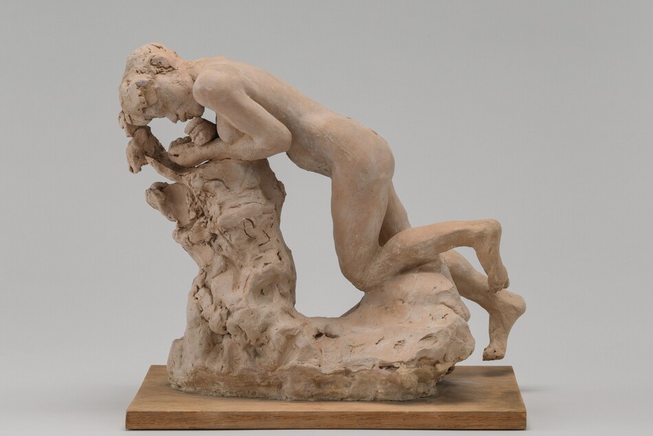 Molded in tan-colored terracotta, a person kneels and leans forward against an L-shaped stump-like form in this freestanding sculpture. The person’s head is to our left in this view, and the breasts are visible. She leans forward onto her forearms with her wrists crossed, so her hands are near her chin and closed mouth. She has short hair and full lips. The area around her eyes is loosely sculpted. One knee is bent and the other is mostly straight as if the foot were reaching toward the ground. The stump is especially loosely formed, and the sculpture sits on a wooden plank. The piece is photographed against a gray background.