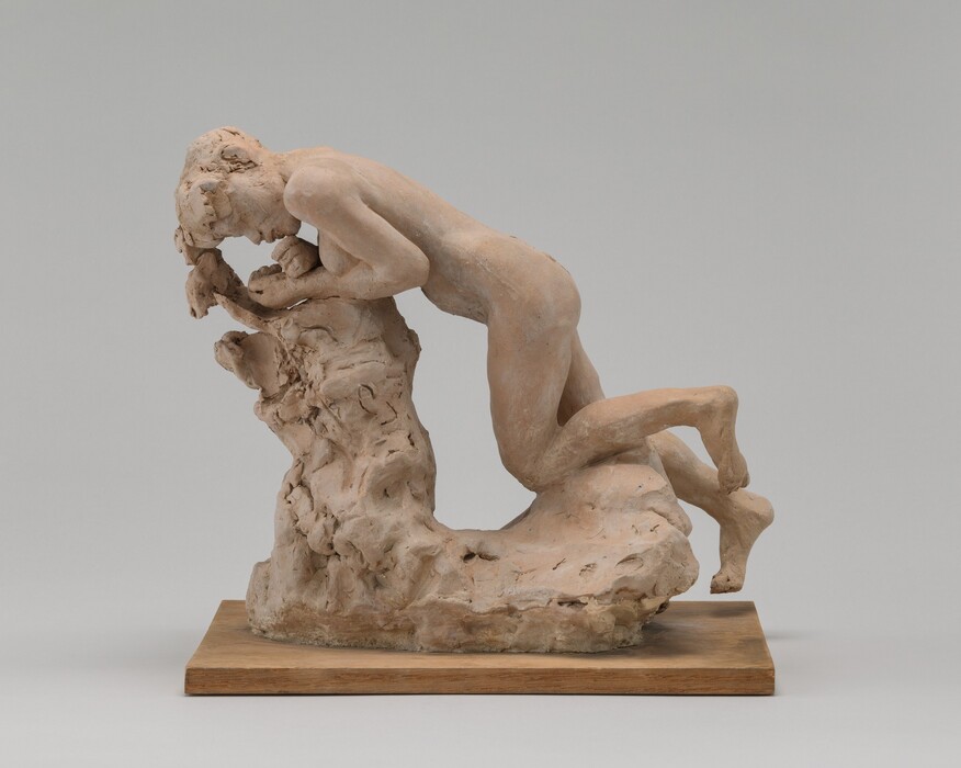 Molded in tan-colored terracotta, a person kneels and leans forward against an L-shaped stump-like form in this freestanding sculpture. The person’s head is to our left in this view, and the breasts are visible. She leans forward onto her forearms with her wrists crossed, so her hands are near her chin and closed mouth. She has short hair and full lips. The area around her eyes is loosely sculpted. One knee is bent and the other is mostly straight as if the foot were reaching toward the ground. The stump is especially loosely formed, and the sculpture sits on a wooden plank. The piece is photographed against a gray background.