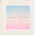The image features a painting of a text with a gradient background. The phrase "THROUGH THE FLOWER" is centered in an elegant, serif font. The background has a smooth gradient transitioning from sky blue at the top to soft pink at the bottom.