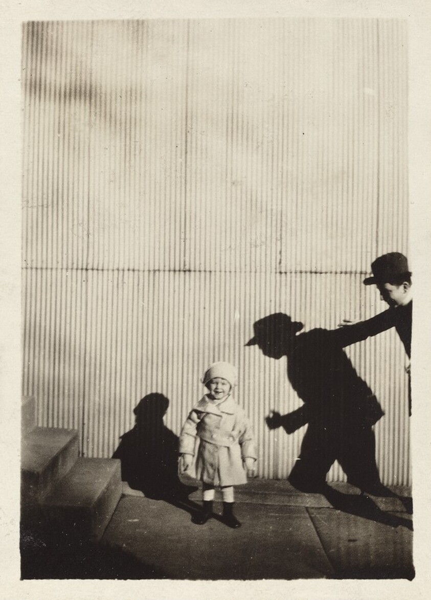 Untitled (Child with shadow of man against corrugated fence)