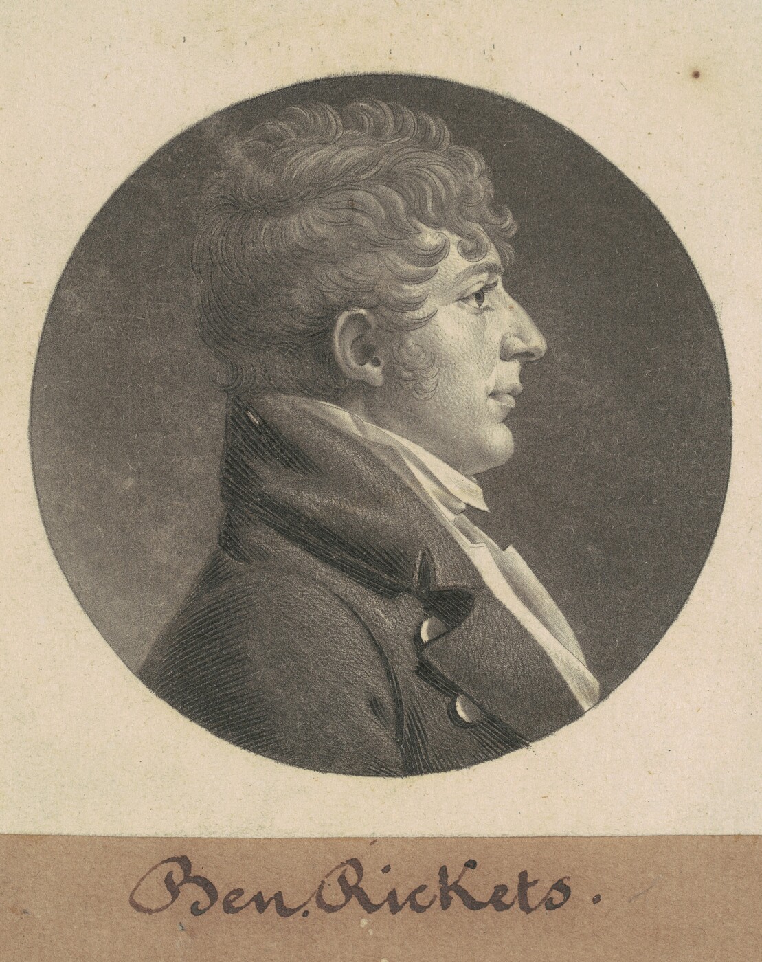 The image shows a portrait of a man in profile view. He has distinct facial features, including a prominent nose and defined lips. His hair is styled in thick, wavy curls. He is dressed in formal attire with a dark coat and a light-colored cravat tied around his neck. The background is plain and dark. The portrait is set within a circular frame, with the handwritten name "Ben. Rickets" below it.