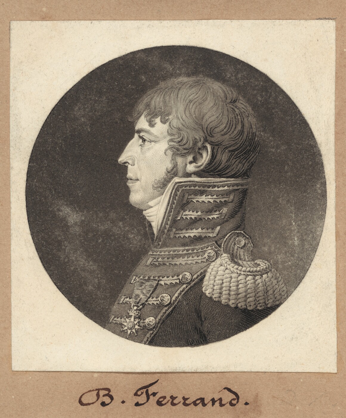 The image is a profile portrait of a man shown from the upper torso upwards. He is positioned to face to the left, highlighting his side profile which includes a nose and a mouth. His hair is short, wavy, and neatly combed back. The man is wearing a military uniform with embroidery, epaulettes on his shoulder, and medals across his chest. There is no jewelry or objects being held. The background is a plain, dark circle, and the image is framed with a rectangular border. The name "B. Ferrand" is inscribed below the portrait.