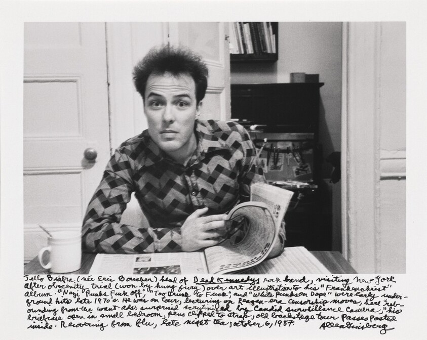 Jello Biafra (nee Eric Boucher) head of _Dead Kennedys_ rock band, visiting New York after obscenity trial (won by hung jury) over art illustrations to his "Frankenchrist" album. "Nazi Punks Fuck Off," "Too Drunk to Fuck," and "White Punks on Dope" were early underground hits late 1970's. He was on tour, lecturing on Reagan-era censorship moves, here "rebounding from the want-ads, surprised scrutinized by Candid surveillance camera," his briefcase open in small bedroom, pens clipped to strap, old backstage tour passes posted inside. Recovering from flu, late night tea, October 6, 1987.