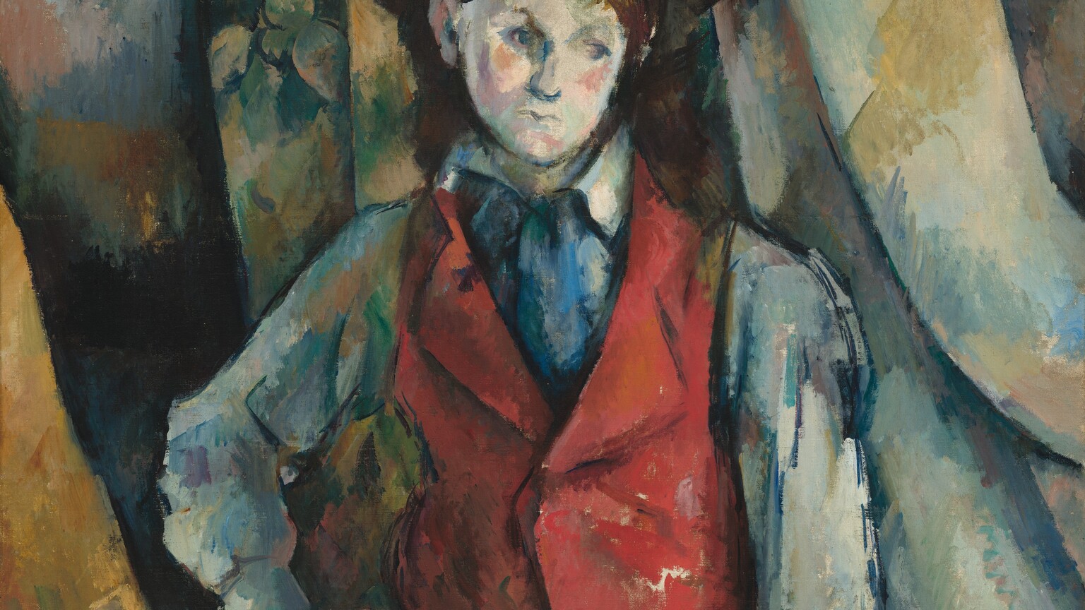 Shown from the thighs up, a boy wearing a crimson-red waistcoat stands against swags of fabric painted with visible strokes in white, sky blue, harvest yellow, and sage green in this loosely painted, vertical portrait. Painted with choppy brushstrokes, the boy has pale, ivory-white skin, blushing pink cheeks, pursed lips, faint eyebrows, and topaz-blue eyes that gaze down to our right. His shoulder-length, dark brown hair is tucked behind one ear under a brown wide-brimmed hat. His red waistcoat is worn over a long-sleeved, slate-blue shirt. The collar of his skirt is slightly flipped up on his right side, to our left, and a swipe of cobalt blue suggests a tie or scarf between the lapels. A band of sapphire blue could be a belt above olive-green trousers, and dashes of navy blue create shadows. His right hand, to our left, is planted on that hip. The other arm hangs straight and loose by his side, those fingertips almost brushing the bottom edge of the canvas. The boy’s body is outlined in dark blue. The drapery behind him falls in folds that sweep gently to our right. The background is painted with patches and swipes of cool blues and greens, and pale golden yellow. One swag of the drapery, over the shoulder to our left, is painted with a loose pattern suggesting leaves. One back post and a sliver of the curving back of a wooden chair peeks into the composition in the lower left corner.