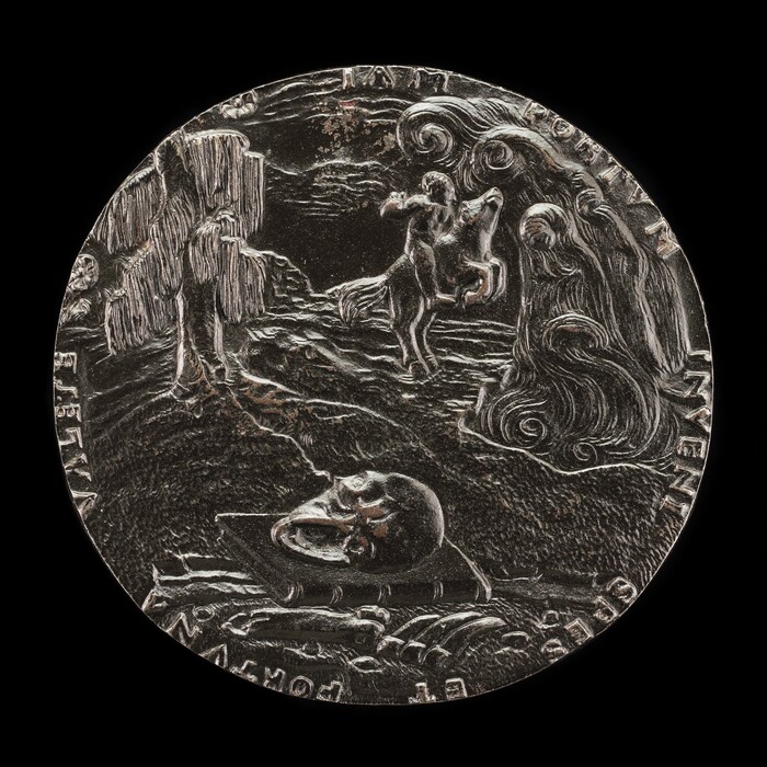 This is a photograph of a medallion. The medallion features a design with a skull on a tablet or pedestal in the foreground, a raised skeleton shape in the mid-ground, a figure on horseback in the background, a tree with hanging branches on the left side, swirling cloud formations in the sky, and engraved text around the edge. The composition suggests themes related to life, death, and existence.