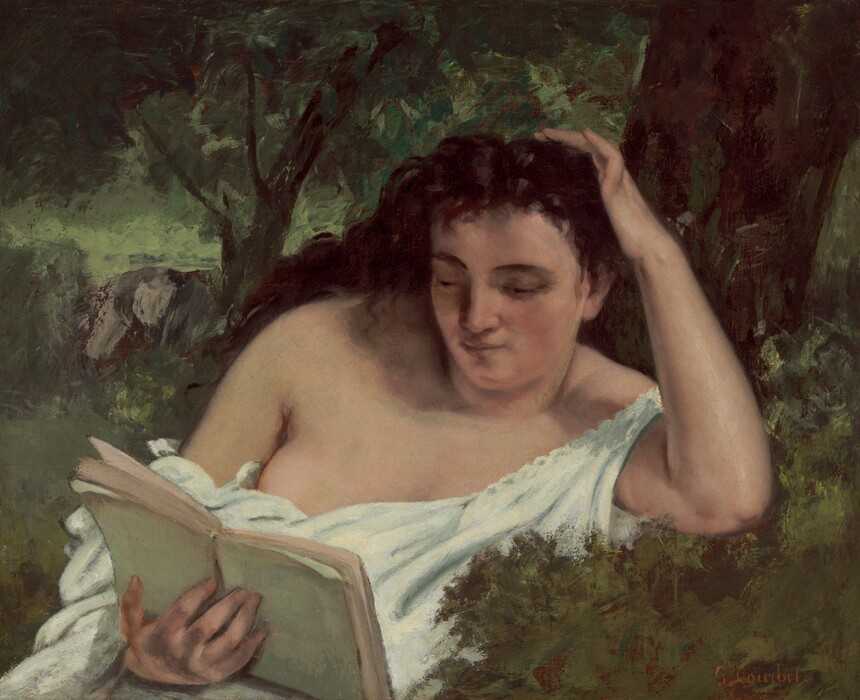 Shown from the waist up, a woman with pale, peachy skin reads a book with one elbow propped on a grassy bank in this horizontal painting. The woman’s body is angled to our right, and she looks down at a pale green-covered book held in her right hand, which is in the lower left corner of the composition. The woman has dark brows over hooded eyes, and her dark brown hair falls loosely behind her shoulders. She has a round face, straight nose, and pale lips. She touches her hair with her left hand, to our right, with that pinky delicately crooked. One strap of a sleeveless, pearl-white chemise falls off the shoulder of that arm, and the dress nestles around her belly, revealing much of the other breast. Leafy trees and gray rocks are loosely painted behind her. The artist signed the painting in the lower right corner, “G. Courbet.”