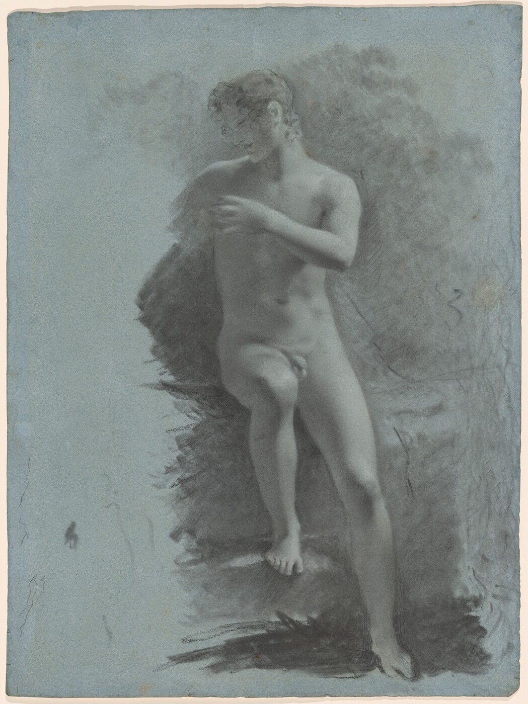 The image depicts a person standing on one leg with the other leg bent and slightly raised. The individual has one hand resting across the chest, and the head is tilted downward. The facial features are soft, with a serene expression, and the hair is curly, framing the face delicately. The person is not wearing any clothing. The background consists of a textured, somewhat indistinct environment, with darker shading around the figure, possibly representing foliage or abstract forms against a light-colored canvas. The image has a monochromatic appearance, executed in shades of gray on a bluish-gray paper.