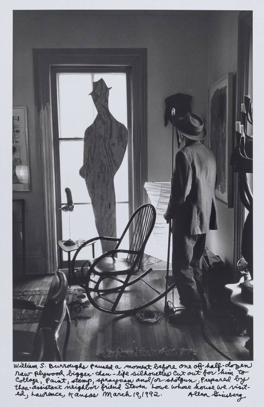 William S. Burroughs paused a moment before one of half-dozen raw plywood bigger-than-life silhouettes cut out for him to collage, paint, stamp, spraycan and/or shotgun, Prepared by then-assistant neighbor friend Steven Lowe whose house we visited, Lawrence, Kansas March 19, 1992.