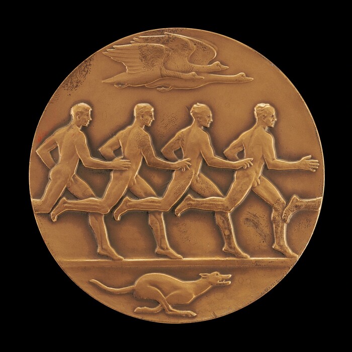 The sculpture depicts a bas-relief of four male athletes running in a line, each engaging in a relay race. Their bodies are depicted in dynamic motion, showing detailed musculature. Above the runners, birds are in flight in the background. Below the athletes, a dog is depicted, also in motion. The sculpture is part of a circular medal made from bronze.