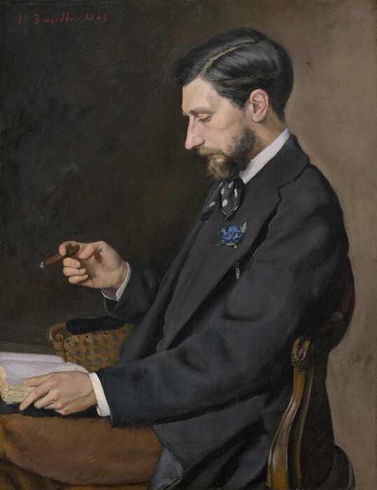 Shown from the lap up, a bearded, pale-skinned man wearing a suit faces our left in profile in this vertical portrait painting. The man looks down at an open book on his lap. He has a prominent, straight nose, high cheekbones, and the corner of his mouth turns down. His gleaming black hair is cut short and parted along the left, and his beard is trimmed. He wears a black vest and suit jacket, a black ascot polka dotted with white, and his white shirt is visible at the high collar and cuffs. A blue flower is threaded through his lapel, and he wears chestnut-brown pants. He holds one side of the book open with his left hand, closer to us, and holds a partially smoked, thin cigar with this other. The wood-framed chair has a curved, round-topped back. The background deepens from peanut-brown along the right to almost black near the top left corner. The artist signed and dated the painting at the top left, “F. Bazille. 1869.”