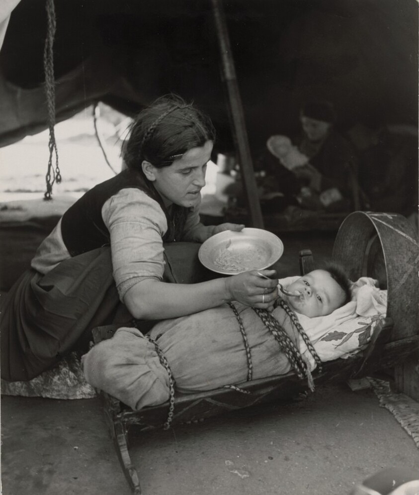 A mother feeds her infant in its peasant cradle, in tent camp of refugees at Ioannina, Greece