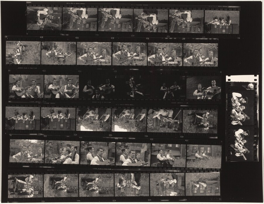 The image is a contact sheet with multiple small black and white photographs showcasing a group of people, predominantly men, playing musical instruments such as guitars. The shots vary in composition, with some showing full bodies while others focus on the upper halves. The individuals are generally seated or standing closely together in small groups. They all have short, well-groomed hair, and their facial features are clear, with some images capturing them smiling or concentrating on playing music. The clothing consists predominantly of formal attire, such as white shirts, ties, and vests. The setting appears to be outdoors with grass visible, interspersed by urban or park-like backgrounds featuring brick walls or trees. There are no visible jewelry items, but the consistent presence of guitars is noted.