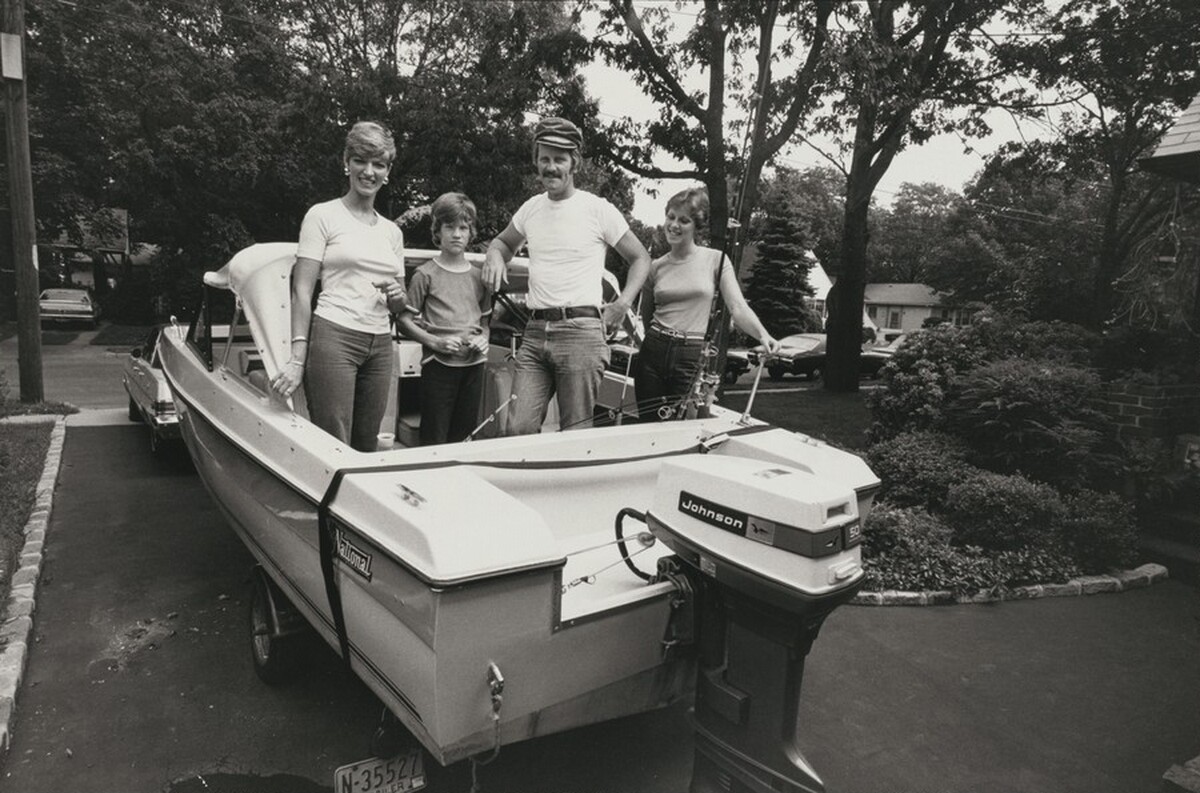A police officer and family pose in their fishing boat, parked in their yard, Long Island, New York