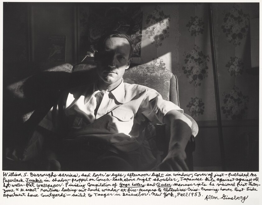 William S. Burroughs serious, sad lover's eyes, afternoon light in window, cover of just-published Ace Paperback Junkie in shadow propped on couch-back above right shoulder. Japanese kite against old hot-water-flat wallpaper. Finishing compilation of Yage Letters and Queer manuscript he visioned first Inter-zone "Market" routines looking out South window at fire escapes & clotheslines criss-crossing Lower East Side apartment house courtyards--sailed to Tangier in December. New York, Fall 1953.