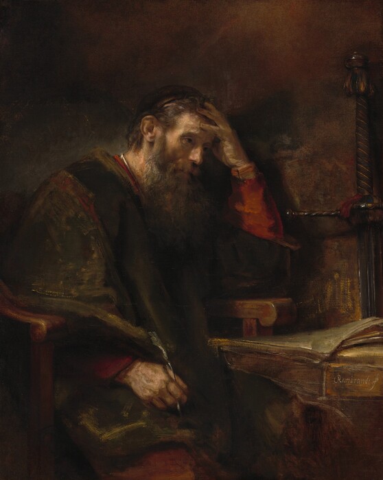 Shown from about the knees up, an older, bearded, pale-skinned man sits at a desk with his head in one hand in a shadowy room in this vertical painting. His body is angled to our right, and he sits in a heavy wooden armchair next to a desk. His left elbow, farther from us, rests on the chair’s arm, and he holds that hand to his forehead. He holds a quill with his other hand, which brushes his knee. He has ash-brown hair covered at the back by a cap and a long shaggy beard. He looks off to our right with dark, shaded eyes. His voluminous brown robe is brushed loosely with golden brown highlights. The rust-red garment under the robe is visible at the sleeves, neckline, and one knee. The desk, to our right, has a stack of papers or parchment. The oversized hilt of a long sword leans against the wall behind the desk. The background is painted with areas of earth and chestnut brown. Some areas of the scene are loosely painted so brushstrokes are visible, especially the brightest white highlights on his collar, the quill, the edges of the parchment, and glints on the sword. The artist signed the painting on the face of the desktop, near the lower right corner: “Rembrandt f.”