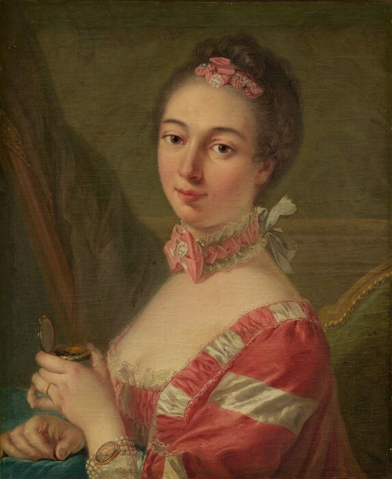 Shown from the chest up, a woman with smooth, pale, peachy-toned skin wearing a carnation-pink and white gown looks at us from this vertical portrait painting. The woman’s shoulders are angled to our left, but she turns her head and tips it to our right to look at us with brown eyes under curving, gray brows. She has an oval face with a straight nose, a hint of a double chin, and her full pink lips are closed in a slight smile. Her ash-brown hair is pulled up and back and curls across the top of her head around pink and white ribbons pleated to resemble flowers. Her square-necked, low-cut bodice is lined with lace across her pale decolletage. The fabric is patterned with thinner white stripes and wider dark pink stripes. A choker tight around her neck has a pink ribbon edged with white lace and tied into a bow at the front of her throat. The necklace is tied on with a white bow at the back of her neck. She wears a gold ring on the fourth finger of her left hand, which is closer to us. On that wrist, four strands of white pearls hold a miniature oval portrait of a pale-skinned person. The woman holds a gold and emerald-green compact with that hand, and the other rests on an aquamarine-blue cushion or cloth in front of her at chest height. She pinches something brown between those fingers, and a few specks of brown are in the box. She sits in a wooden chair upholstered with moss green on the back. A curtain or other swath of muted purple fabric is to the left, and the wall behind her has chair-rail molding and is painted soft leaf green.