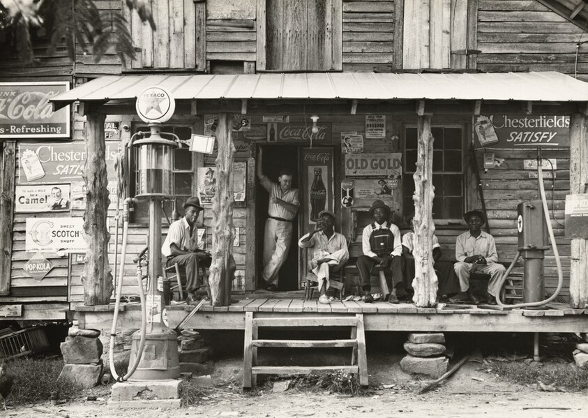 Country store on dirt road. Sunday afternoon. Note the kerosene pump on the right and the gasoline pump on the left. Rough, unfinished timber posts have been used as supports for porch roof. Negro men are sitting on the porch. Brother of store owner stands in doorway, Gordonton, North Carolina