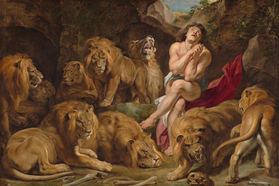 A nearly nude, muscular man with pale, peachy skin sits in an underground cave among seven male and two female lions in this horizontal painting. The man sits to our right of center with his legs crossed, elbows close to his body with hands clasped by his chest. His head tips back to look up through a small opening above. He has long, wavy, chestnut-brown hair and dark eyes. A white cloth wraps across his hips, and he sits on a scarlet-red swath of fabric draped up over a rock next to him. The nine lions stalk, sit, or lie down around the man. One male lion next to the man, to our left, opens his mouth with his head thrown back, curling tongue extended beyond long fangs. A human skull and other bones are strewn on the dirt ground close to us. The rocky cave curves up around the animals and man to a narrow, round opening showing blue sky above.