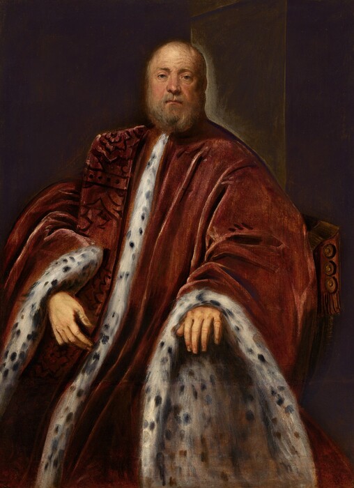 Shown from the shins up, a pale-skinned, balding, bearded man wearing a voluminous rust-red robe lined with black-speckled white fur looks out at us in this vertical portrait painting. The man sits in a wood-framed chair with a curving seat. His body angled slightly to our left, but his face turns to us. He looks out with dark gray eyes under a lined forehead, one eyebrow slightly cocked. He has a rounded nose, thin lips, and paunchy cheeks. A few wisps of gray hair are suggested across the top of his mostly bald head, and his gray beard is trimmed. His left hand, to our right, rests on the terminus of the chair’s arm, and his other hand rests in front of his belly, presumably with that elbow on the other arm. His robe falls heavily in deep folds, and the wide openings of the sleeves continue down and off the bottom edge of the canvas. The front of the robe and the insides of the sleeves are lined with white fur dotted with black. A scarf-like band of fabric brocaded with dark red-on-red drapes over one shoulder. The background is charcoal gray except for a dark, olive-green shape suggesting a doorway over the man’s left shoulder.