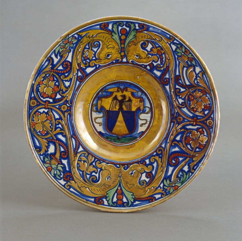 Plate with border of foliate scrollwork with dolphin heads and cornucopias; in the center, shield of arms of Vigerio of Savona