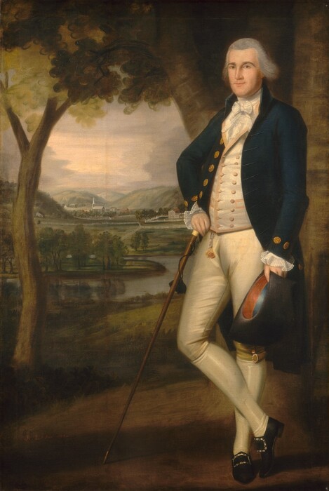 A pale-skinned man wearing a white waistcoat, navy-blue coat with tails, knee-length britches, and white stockings stands in front of a deep landscape in this vertical portrait painting. The man nearly fills the right half of the composition. He stands with one ankle crossed in front of the other and his body angled to our left. He looks out at us with brown eyes under wide, dark gray brows. He has a round face with a wide jaw, a straight nose, and his thin, pale pink lips are closed. His gray hair is brushed back from his forehead and sweeps down over his ears. A white cravat is tied in a bow around his neck under a cream-white waistcoat, which is trimmed with pale peach and has two rows of peach buttons down the front. The jacket has gold-colored buttons, and translucent, ruffled cuffs flare out at the wrists. A fob hangs from his parchment-white pants, which are fastened with an oval-shaped, diamond-encrusted buckle on the outside of the knee facing us. His stockings are pearl white, and his black shoes have square silver buckles. He holds a black hat in his left hand, to our right, and his other hand rests on the end of a waist-high wooden walking stick, which angles out to our left where the brass end is braced against the ground. A brown form behind him and to the right could be a column, edge of a building, or a tree trunk. A thick trunk angles out on the far side of his head, and a smaller tree grows up the left side of the composition. Grassy fields reach back to a winding river and a town with a church spire, manor house, and other buildings tucked among hills. Lavender-gray clouds press in to either side of a sunset sky lit pale pink at the center. The artist signed and dated the painting in the lower left corner, "R. Earl Pinxt 1789.”