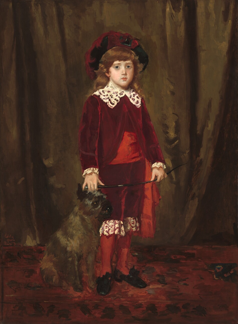 A young boy with pale skin, wearing a burgundy-red suit and floppy hat, stands facing and looking at us with a gray terrier dog at his side in this vertical portrait painting. The boy has large, slate-blue eyes, rounded smooth cheeks, a small nose, and his pink bow lips are closed. His thick blond hair falls in waves across his forehead and down to his shoulders. His body is angled slightly to our right and he holds a riding crop with both hands in front of his body. The sheen on his burgundy-red jacket, and knee-length pants suggests they are velvet. A wide, lace collar comes to points on his chest. Lace cuffs peek out at his wrists, and the lower hem of his pants, around his knees, is edged with wide lace. A broad, slightly brighter ruby-red sash wraps around his waist and hangs by his left hip, on our right. His calves are covered in stockings of the same brighter red. His black shoes seem to be tied with a ribbon, but this area is loosely painted. His right hand, to our left, might brush the head of the dog sitting next to the boy’s leg. The dog has shiny, charcoal-gray fur and a black nose, ears, and eyes. The dog sits angled and looking off to our right. They are on a brick-red carpet with dashes of black that suggest a pattern, and an olive-green drape hangs behind them. The portrait is loosely painted throughout, but the brushstrokes are especially visible in the rug, background, and dog. The painting is inscribed near the lower right corner: “Eddy from Aunt Mary.”