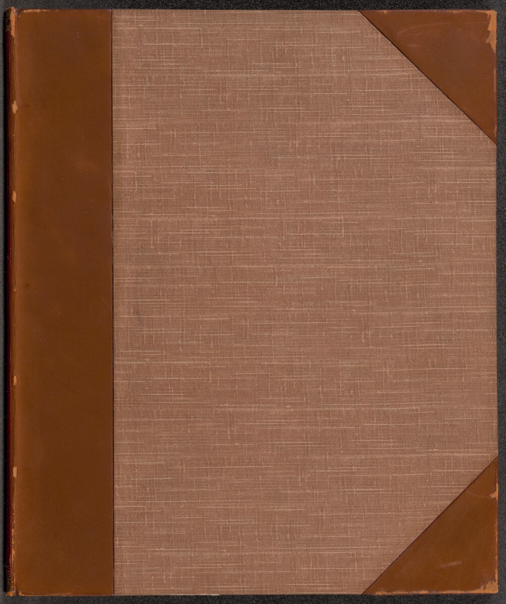 This is a photograph of a book cover. The cover features a textured fabric material in a neutral brownish tone, with reinforced corners and spine made of a smooth, slightly darker brown material resembling leather. The stitching pattern on the fabric gives it a subtle crosshatch design. The book cover does not contain any visible text, illustrations, or embellishments.