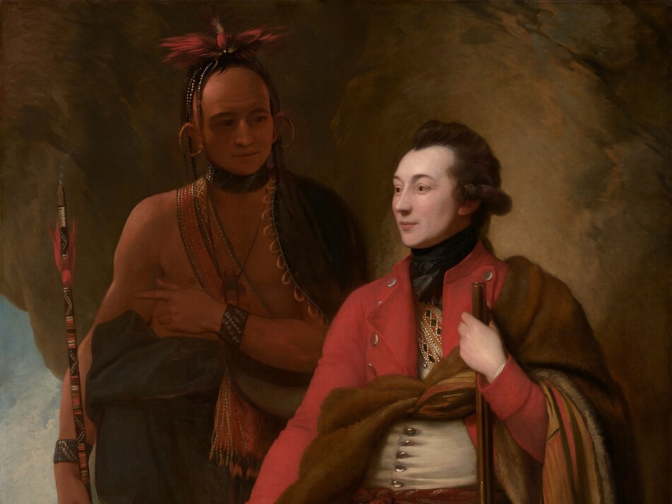 A man with pale white skin sits and a man with light brown skin stands in front of a cave-like, rocky outcropping in this vertical portrait painting. The light-skinned man closer to us has dark brown hair, and the light falls more strongly on him. He sits propped on or against a rock with his body angled to our left, and he looks off into the distance in that direction. He wears a scarlet-red overcoat, a white waistcoat, and moccasins. What appears to be an animal skin painted on the underside with red, tan, and black geometric patterns is tied around his chest and falls over his left arm, on our right. With that hand, he holds a musket like a walking stick. He also holds a black cap ornamented with beads and feathers on his other knee. The man with brown skin stands in shadow behind the other man, to our left. His body faces us, and he looks at the seated man. A dark cloak encircles his shoulders and is gathered around his waist. A strap crosses his bare chest and the strap, bracelets, and a feathered headdress seem to be beaded. Large gold rings curve from his earlobes up over his ears. A puff of smoke emerges from the top of the long, painted stick he holds, suggesting  it is a pipe. He holds his left hand, on our right, at his chest, and points subtly to our left, perhaps to the landscape seen through a break in the rocky outcropping. There, in front of a waterfall in the distance, a small group of people with light brown skin gather around a camp fire in front of a tent-like structure.