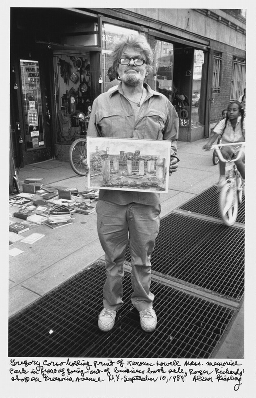 Gregory Corso holding print of Kerouac Lowell Mass. Memorial Park in front of going-out-of-business book sale, Roger Richards' shop on Greenwich Avenue N.Y. September 10, 1989