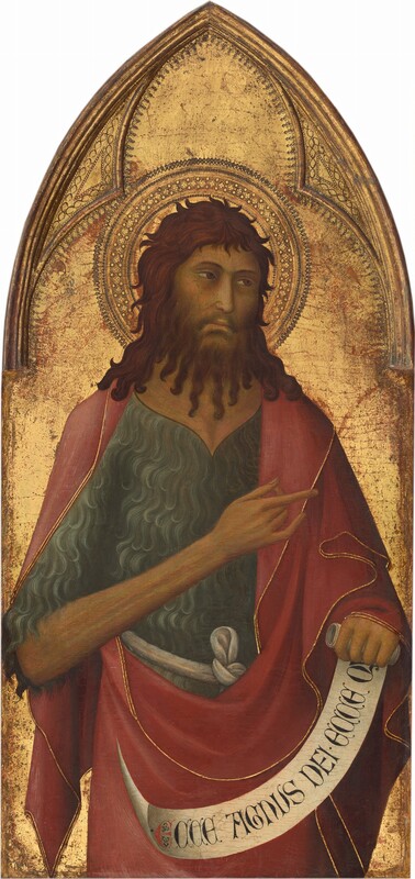 Shown from the hips up, a bearded man wearing a textured shirt under a cranberry-red robe stands in front of a gold background in this vertical painting, which comes to a pointed arch at the top. The man’s pale skin has a green-gray cast in the shadows, but his cheeks are pink. His body faces us, but he looks off to our right with slitted, brown eyes under curving brows. He has a long, straight nose and his lips are closed. His shoulder-length brown hair curls around his head, and his beard falls to his chest in long ropes like thick fringe. His textured shirt is topaz blue, and the red robe is edged with gold. He holds his right arm, to our left, so it crosses his chest as he points to our right. A scroll in the other hand reads, “ECCE AGNUS DEI.ECCE Q.” A patterned halo is punched and incised into the gold background. Molding creating a three-lobed shape over the man’s head is punched with dots and marquis-shaped designs. Areas of brick red show through some areas of the gold background.