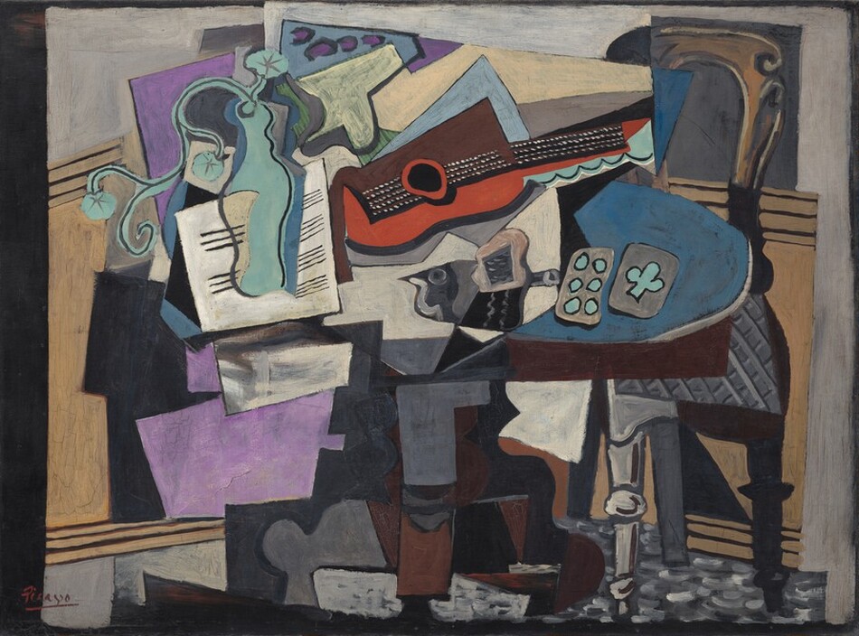 Abstracted objects, including a guitar, vase, papers, and playing cards, are gathered on a tabletop in this horizontal still life painting. The objects are made up of areas of mostly flat color and many are outlined in black, creating the impression that the some shapes are two-dimensional and assembled almost like a collage. The brown table has an oval top and a curving pedestal foot. At the center of the jumble on the tabletop, a guitar lies on its side with the neck facing us and reaching to our right. Beneath the black fretboard and neck, the curving form of the guitar is painted tomato red. The upper half is represented by a squared-off brown form. The guitar seems to rest atop or in front of an array of stacked shapes, like splayed pieces of paper, in white, lavender purple, and pale blue. A curving form painted in turquoise to our left seems to be a vase holding a spray of three flowers. The vase is shown against a white square painted with horizontal black lines, like sheet music. A dark gray form at the middle of the table, beneath the guitar, could be the silhouette of a bird facing our left. Just to the right of the bird, a pair of playing cards lie on a blue area. Painted in turquoise against gray, one card has six dots and the other one club. A chair with a curved, arching top and a gray upholstered seat is pulled up to the table to our right. The front left leg is light gray with turned knobs near the foot and halfway up the leg; the right leg is painted black, as if in shadow. Panels of pale tan suggest wainscotting behind the table beneath a pale gray wall across the background. The overall impression of the painting is fragmented as even single objects seem to be broken up into planes and areas of color. The artist signed and underlined his name with red paint in the lower left corner: “Picasso.”