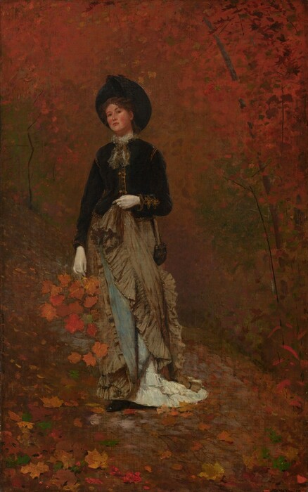 A woman with smooth, pale skin and wearing a hat, long dress, and gloves, stands holding a bunch of pumpkin-orange leaves against a background of trees painted with touches of rust orange and pine green in this vertical painting. The woman tips her head back slightly to look at us with dark eyes under arched eyebrows. Her cheeks are flushed and her coral-pink lips closed. Her round black hat perches on the back of her head and she has an inky black, long-sleeved, hip-length jacket with bronze trim at the shoulders, cuffs, and down the front. A gauzy bow is tied at her neck. Her left elbow, on our right, is bent and she holds up her tan-colored, ruffled skirt with a white-gloved hand. The raised skirt exposes sky-blue lining and white, ruffled flounces at her feet. Her right arm, on our left, hangs at her side and holds the handle of a basket. Deep marigold-orange leaves cascade out of the basket. One black shoe peeks out from under her long skirt. She stands on a hill carpeted with crimson-red, tawny-brown, golden yellow, and forest-green leaves. The space behind her is filled with touches and dabs of red, orange, brown, black, and tan.