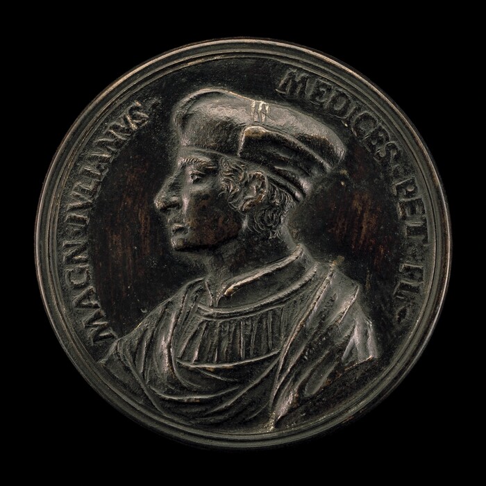 The sculpture shows the profile of a man facing left, wearing a Renaissance-style hat and robes. The material appears to be dark metal, possibly bronze. The image is within a circular medallion with inscriptions around the figure. The craftsmanship emphasizes fine details, with defined folds in the clothing and hair texture.